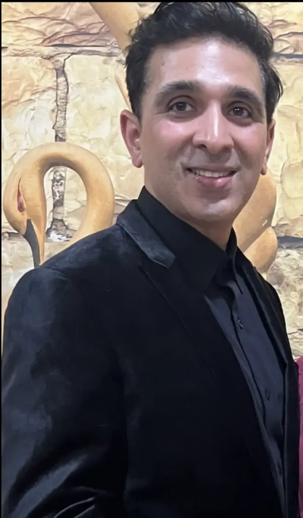 Man in black suit smiling at camera.